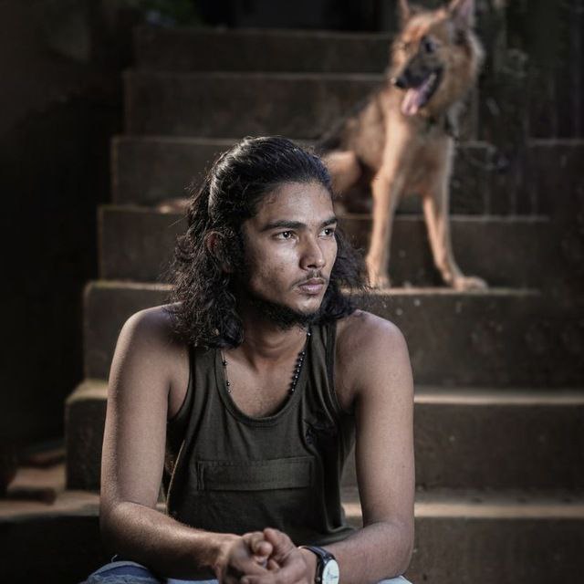 a person sitting on stairs with a dog standing on the side